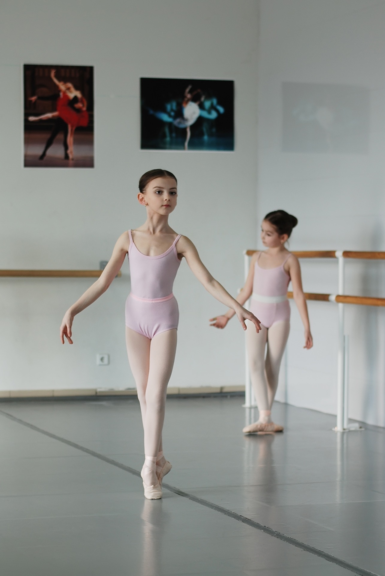 Two young ballerinas dancing in a ballet studio.